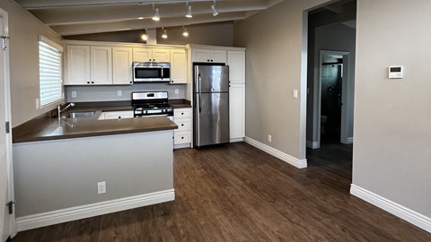 an empty kitchen with stainless steel appliances and white cabinets